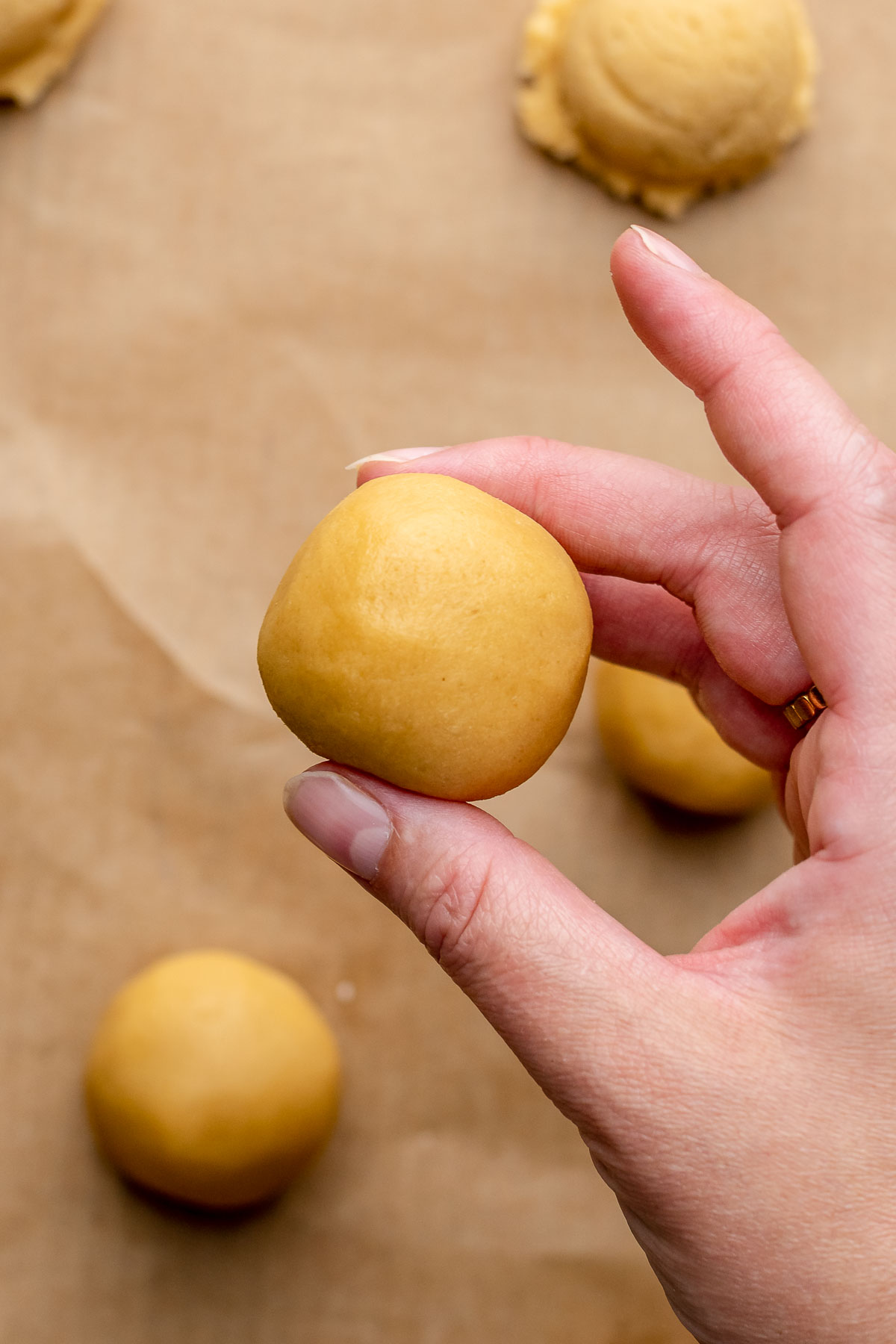 A hand holds a rolled dough ball.