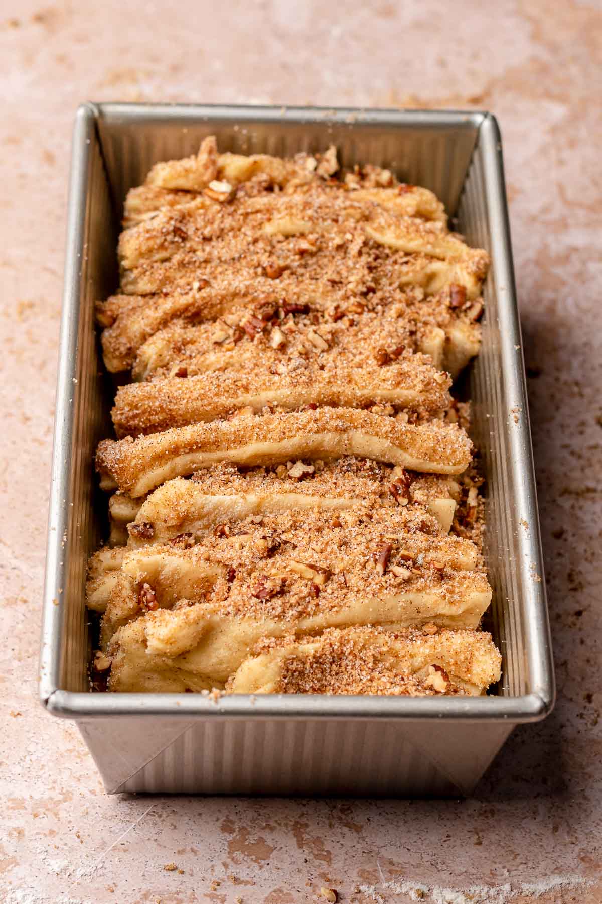 Dough pieces layered upright in a loaf pan before rising.