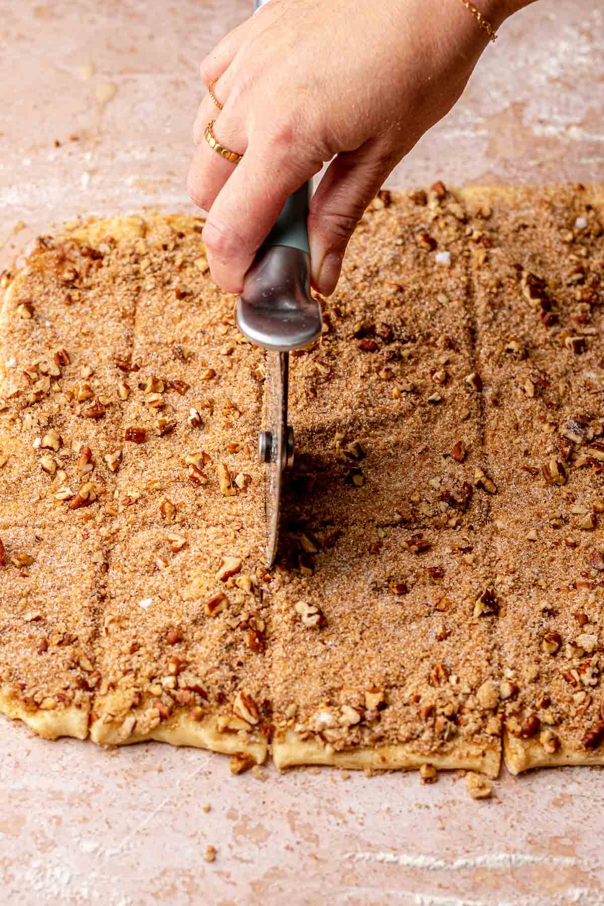 A pizza wheel cuts dough into small rectangles.