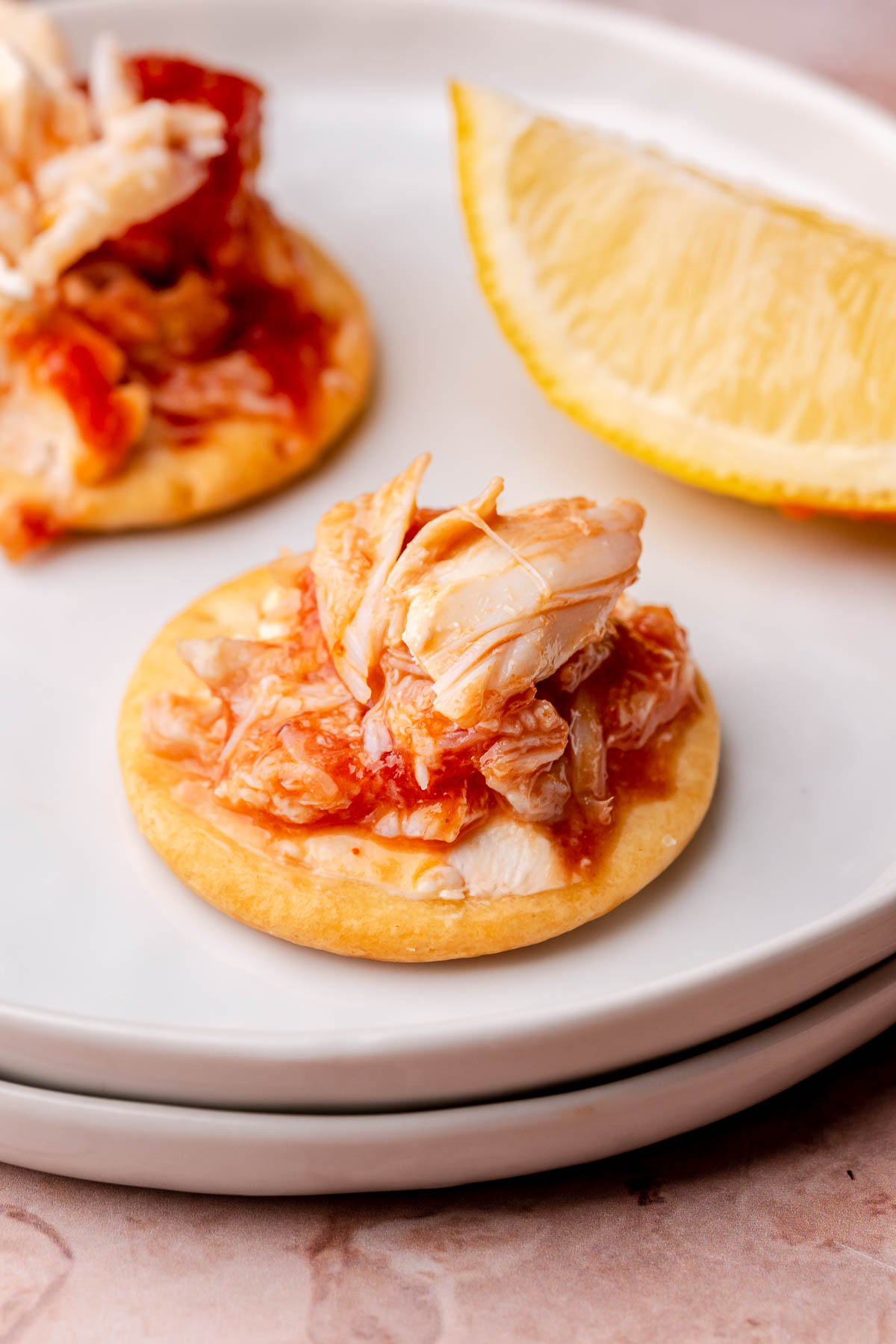 Crab cocktail dip on a cracker sitting on a plate.