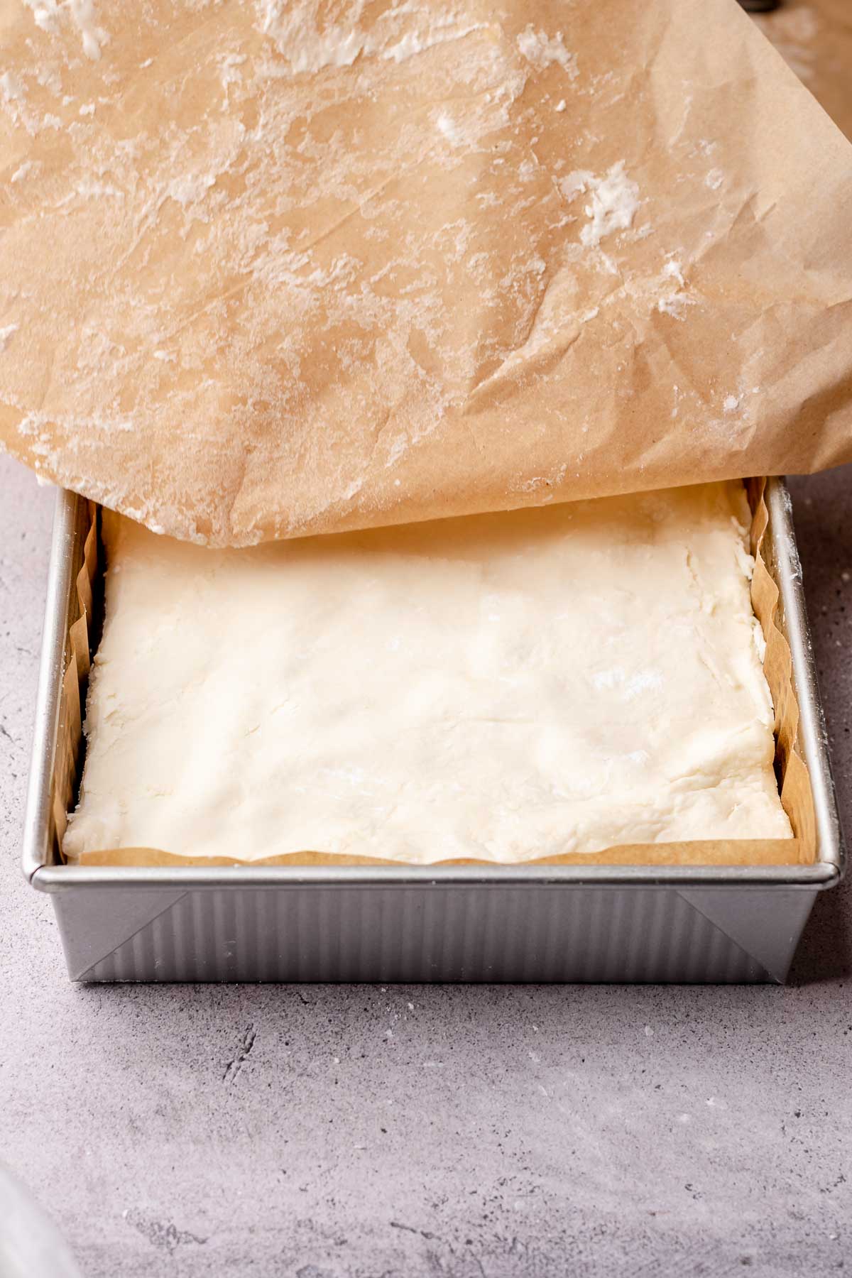 Peppermint filling is added on top of brownies in a square pan.