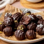 Brownie truffles on a plate. The top one has a bite removed.
