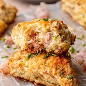 A stack of ham and cheese scones. The top scone has a bite removed.