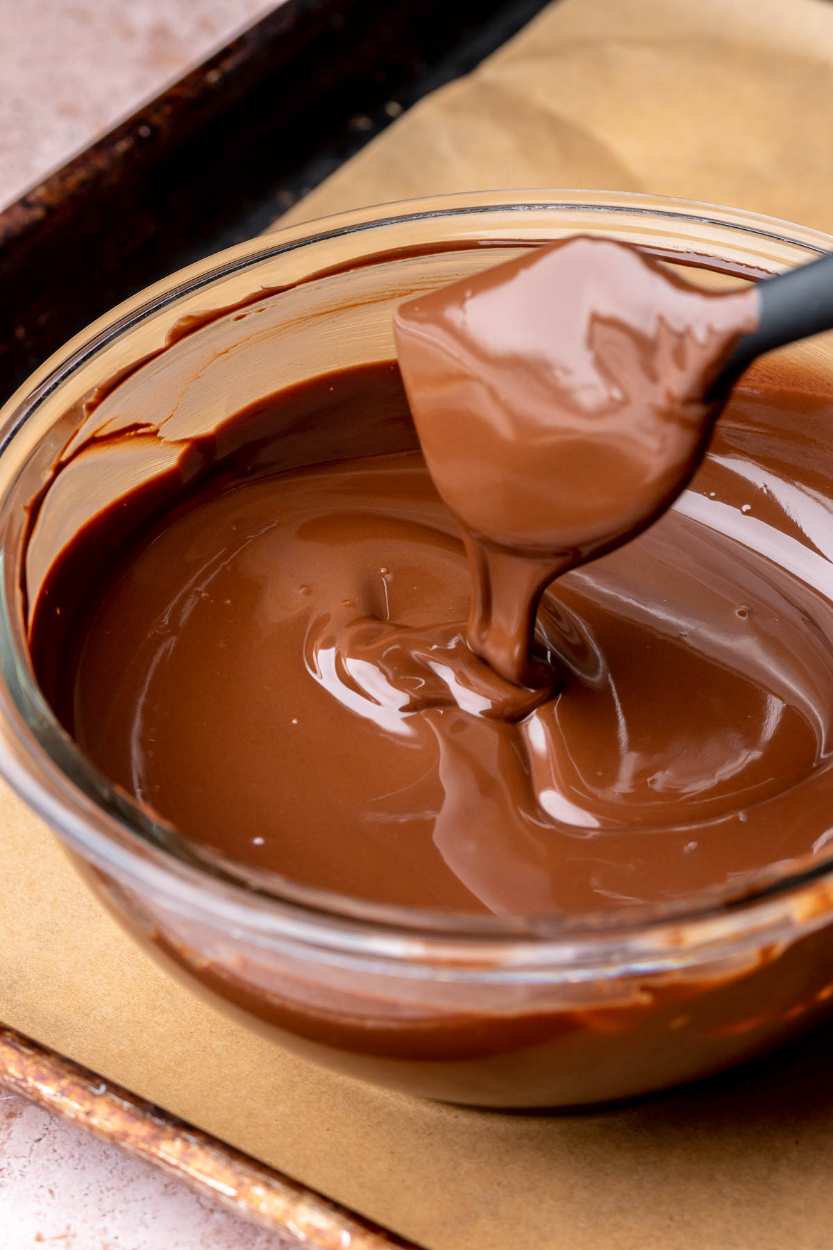 Melted chocolate runs off a spatula into a bowl.
