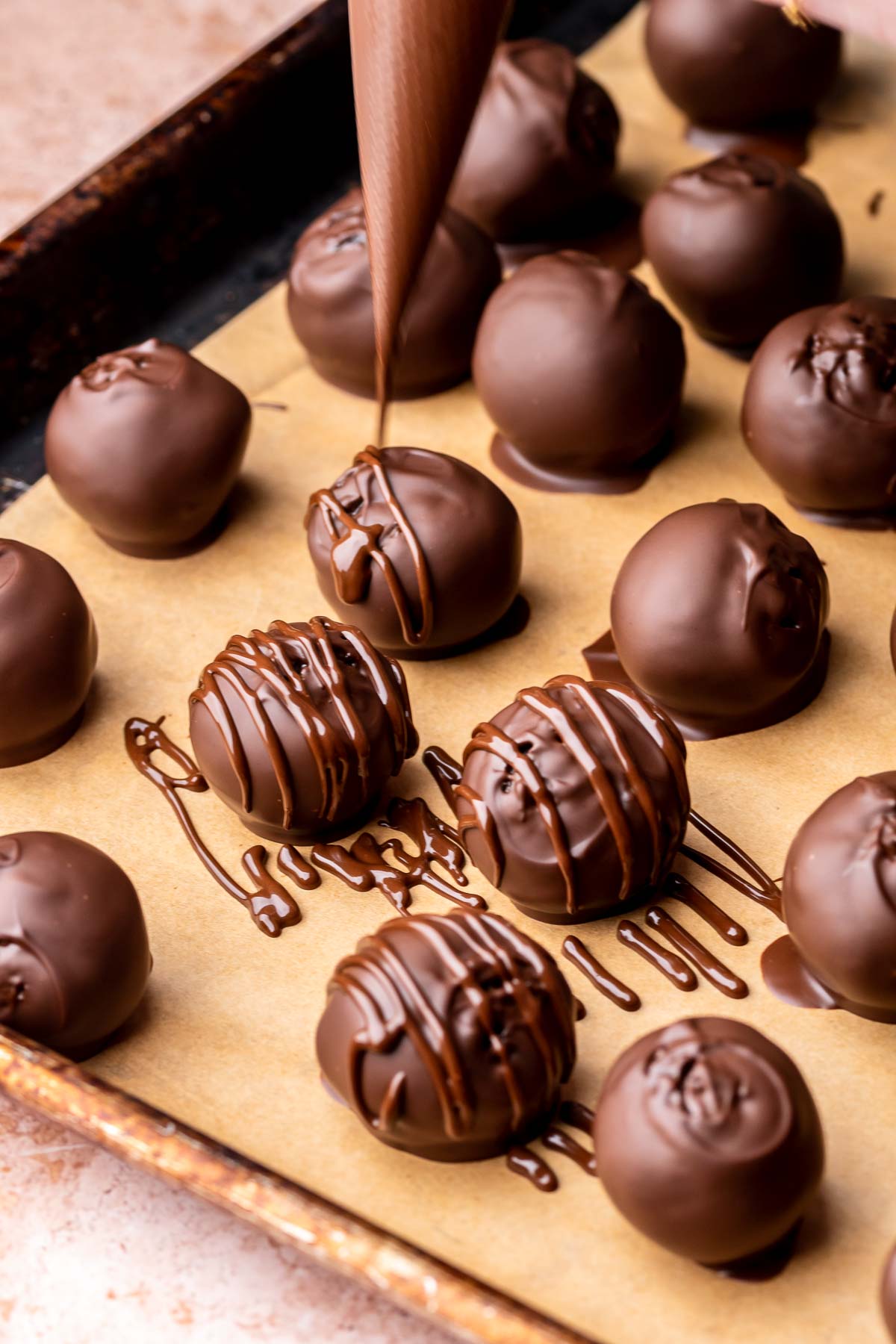 Melted chocolate being drizzled on dipped brownie truffles.