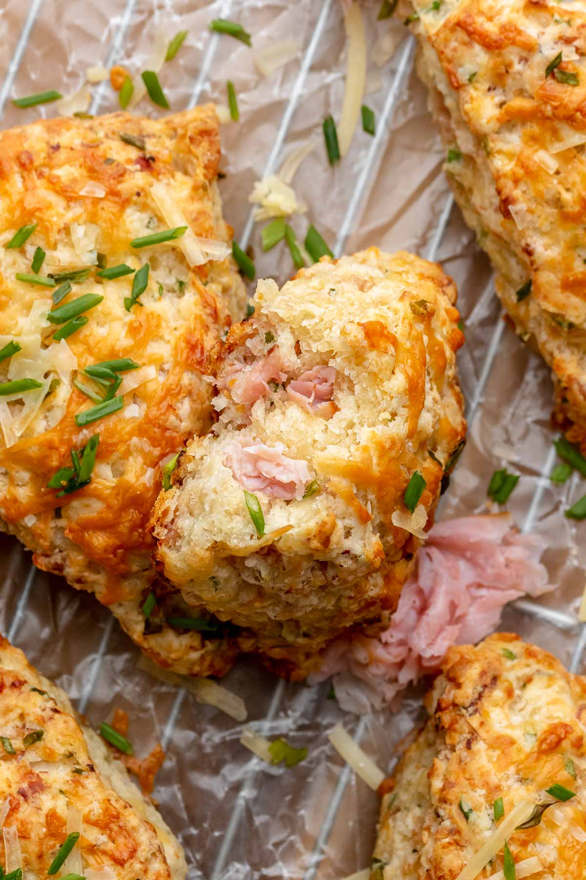 A stack of ham and cheese scones. The top scone has a bite removed.