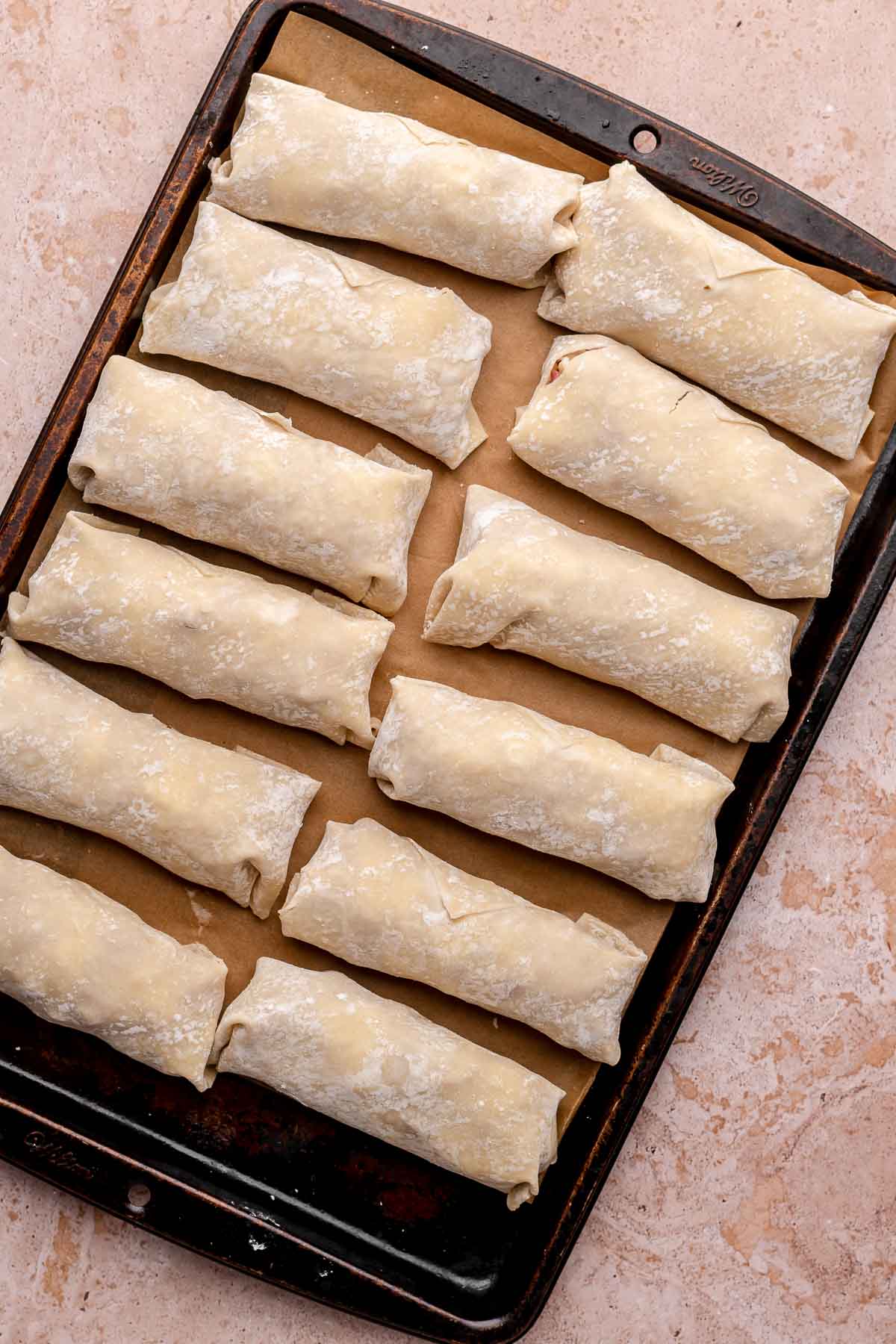 Filled egg rolls on a sheet pan.