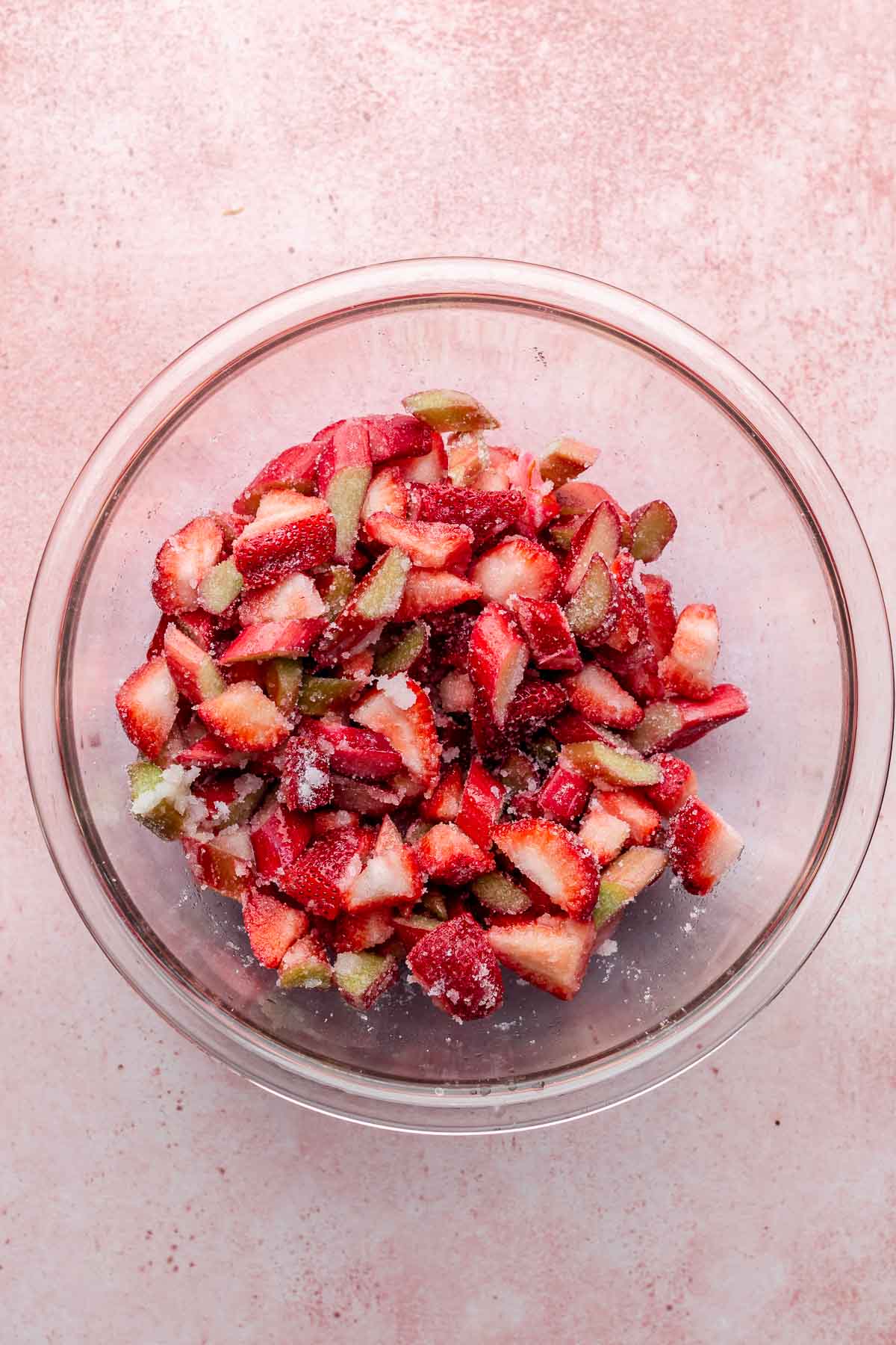 Chopped strawberry and rhubarb in a bowl with sugar.