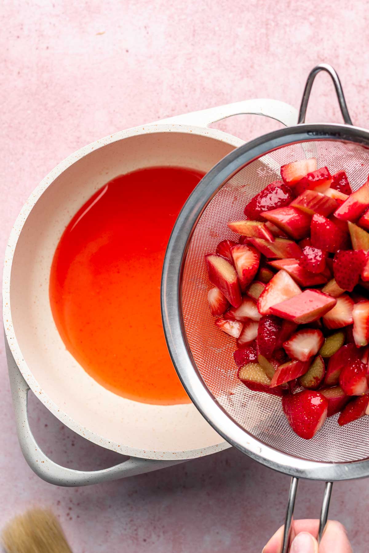 Fruit in a colander and juices in a pot.