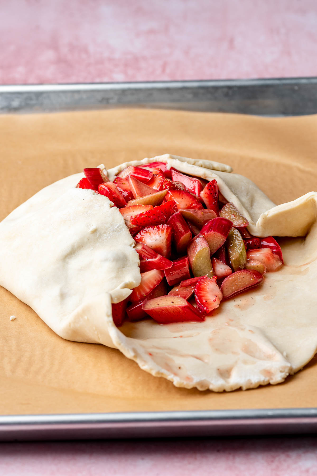 Pie crust edges being folded around fruit.