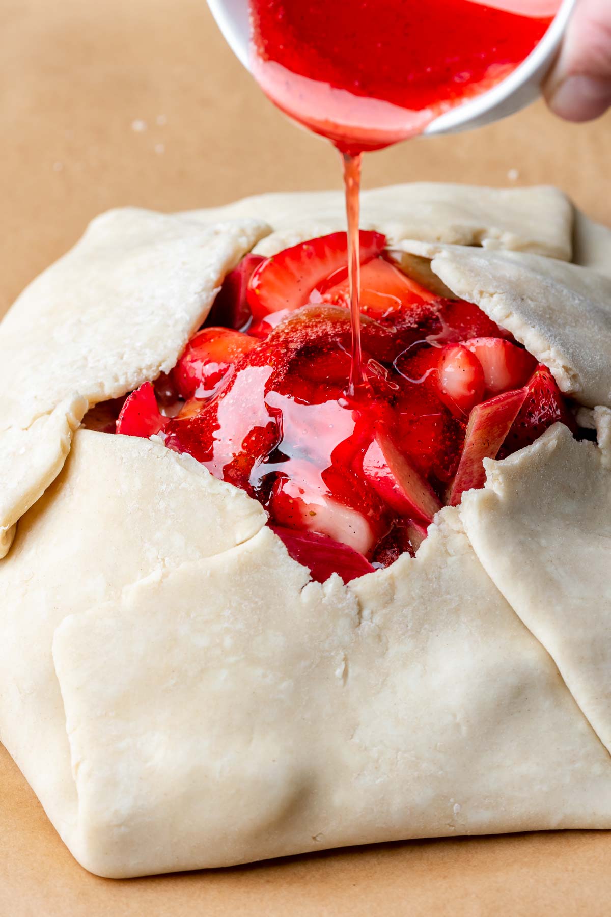 Reduced fruit juice being poured into the center of an assembled galette.