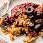 Cherry crisp on a plate with a spoon.