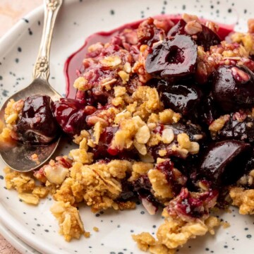 Cherry crisp on a plate with a spoon.