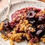 Cherry crisp on a plate with a spoon.