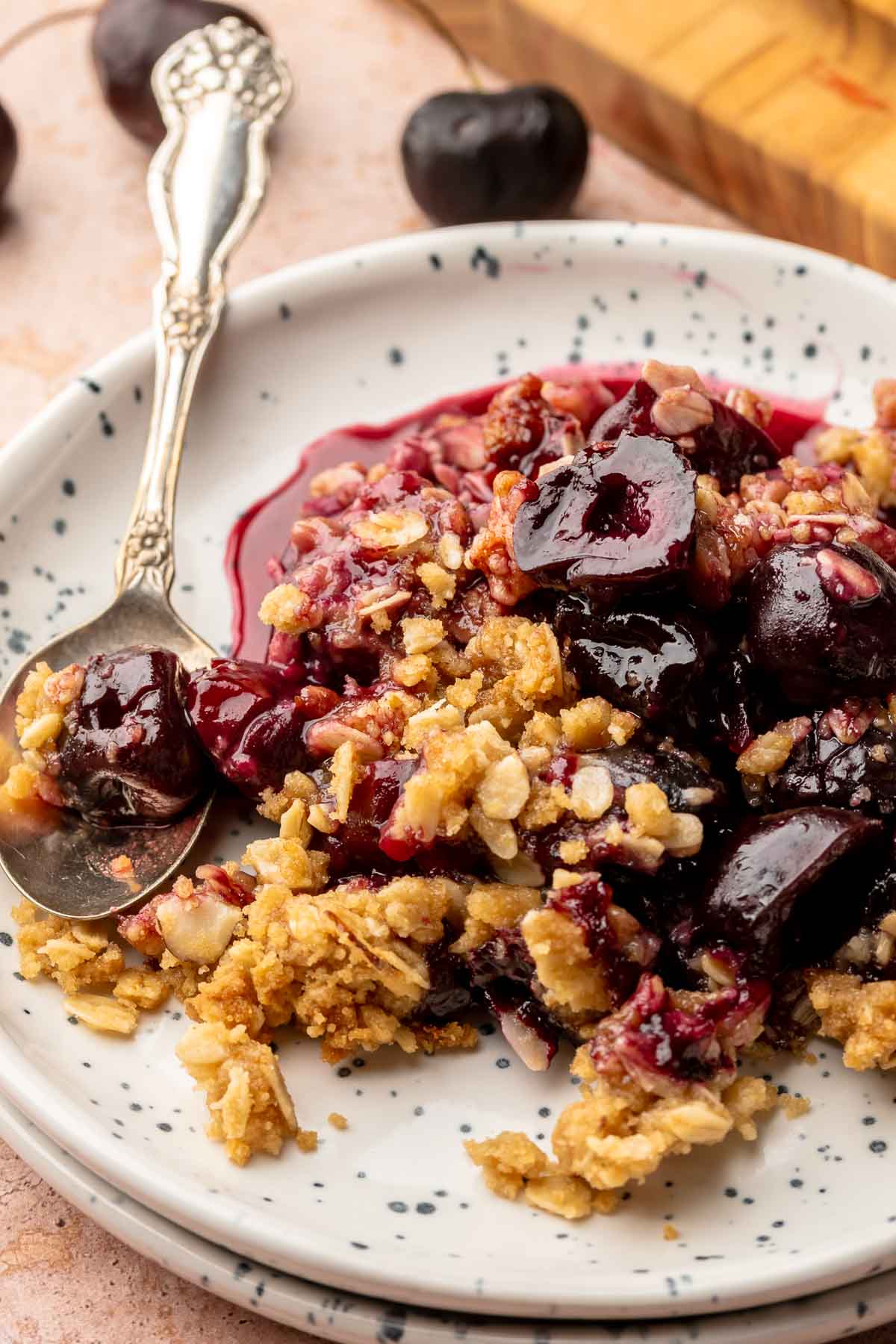 Cherry crisp on a plate with a spoon.