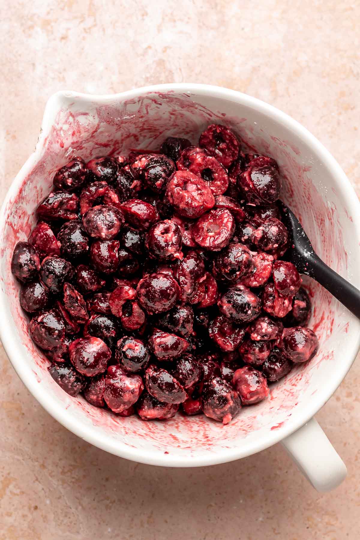 Chopped cherries in a mixing bowl with a spoon.