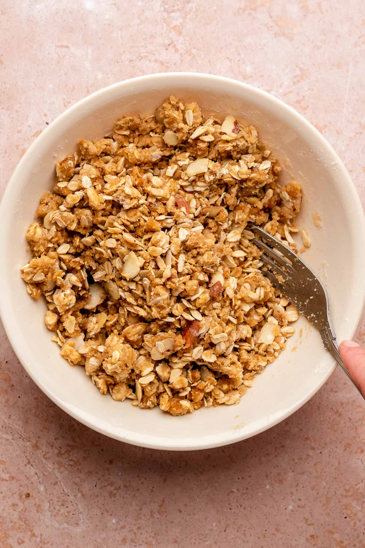 A fork mixes almond oat crumble topping.