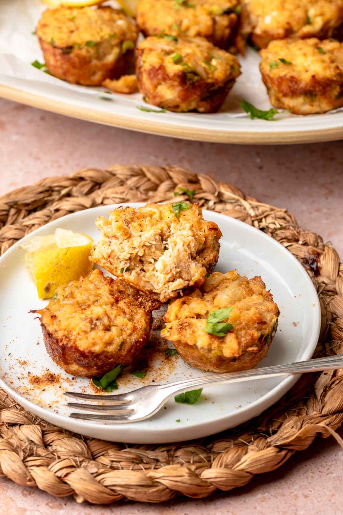 Three mini crab cakes on a plate. One crab cake is half eaten.