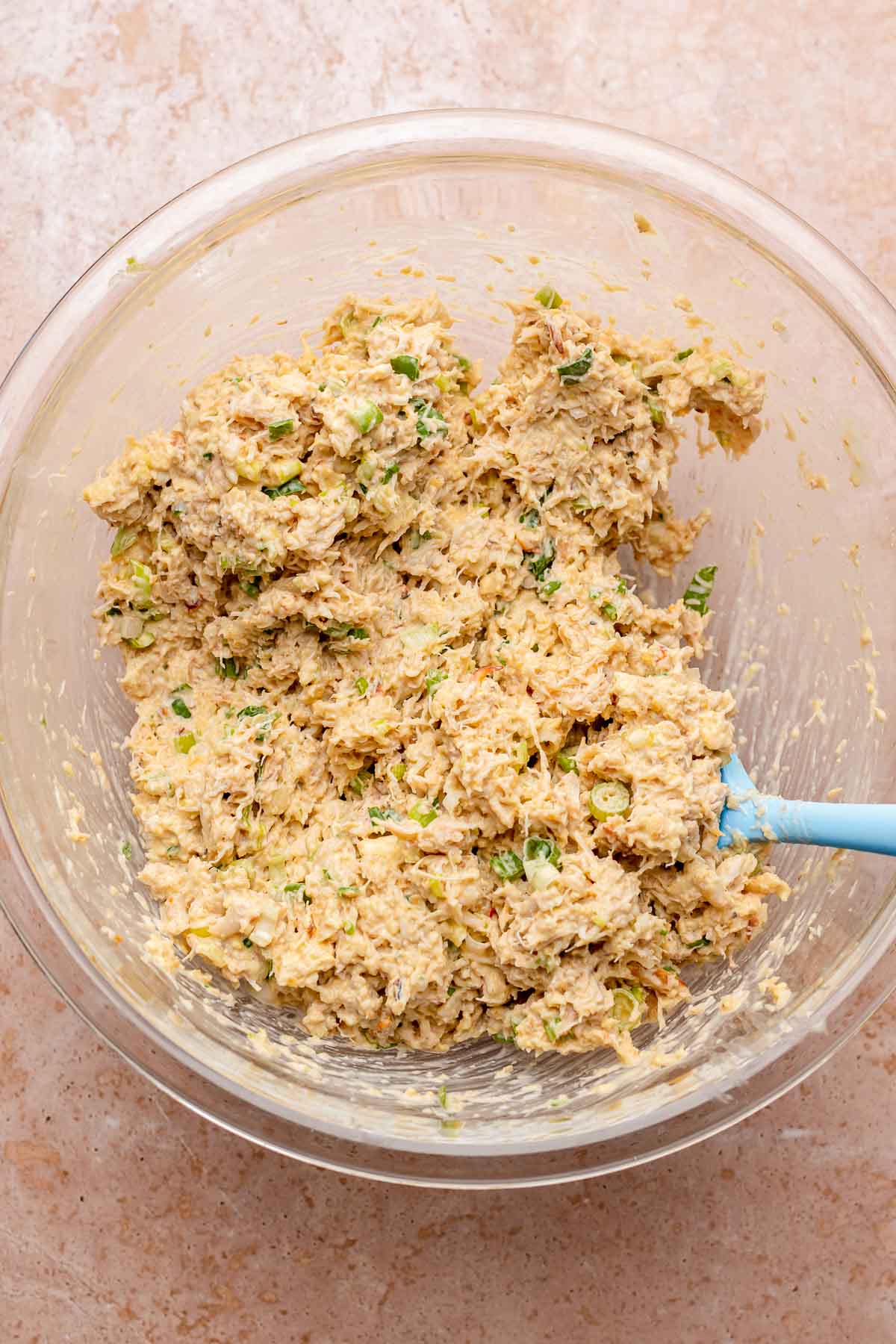 A spatula mixes crab cakes in a bowl.