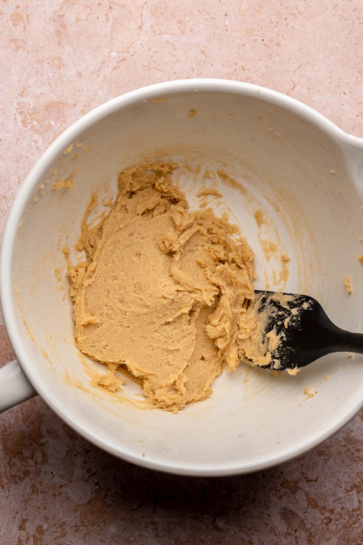 Creamed butter and sugars in a bowl with a spatula.