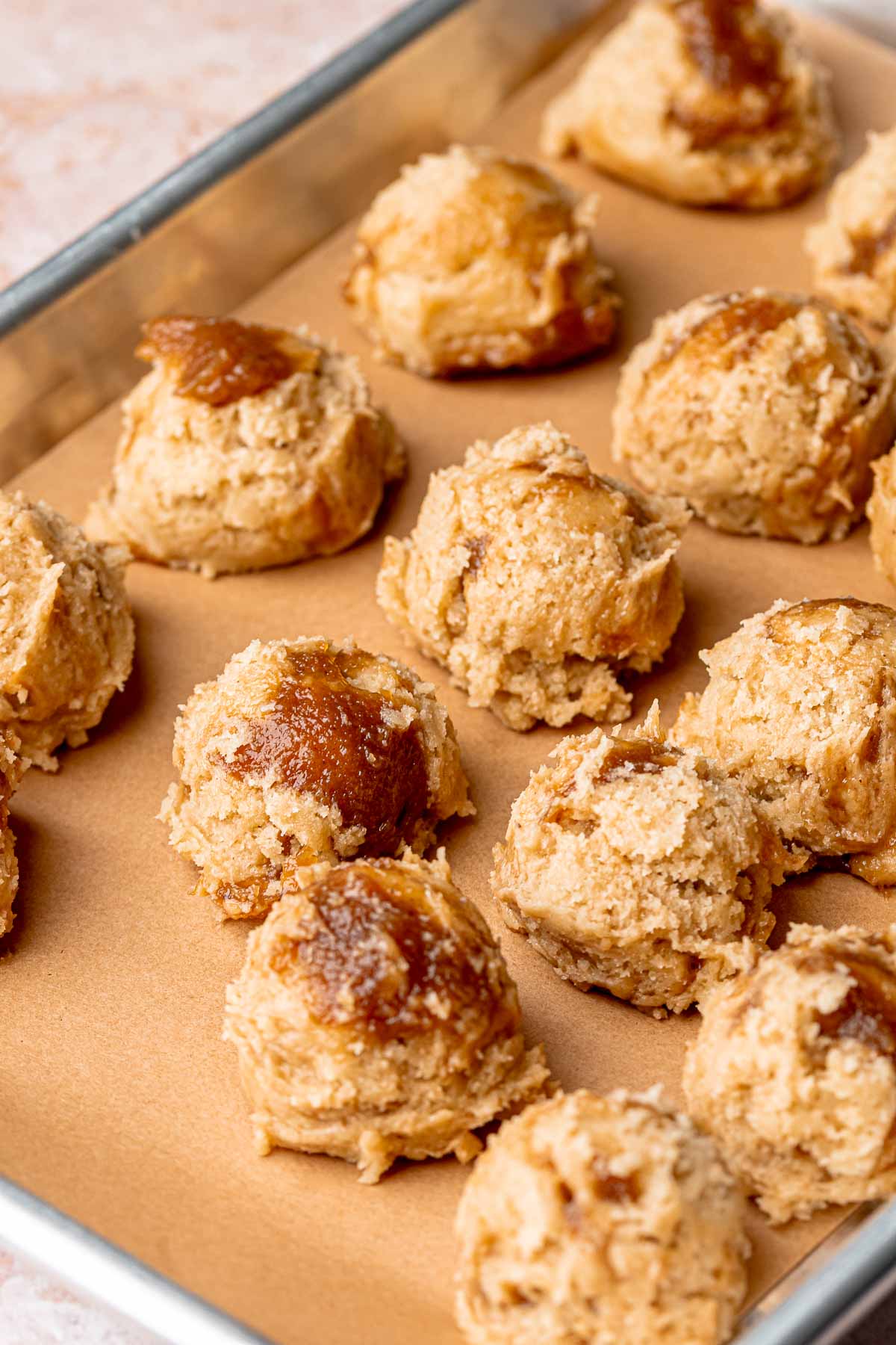 Scooped balls of apple butter cookie dough on a sheet pan.