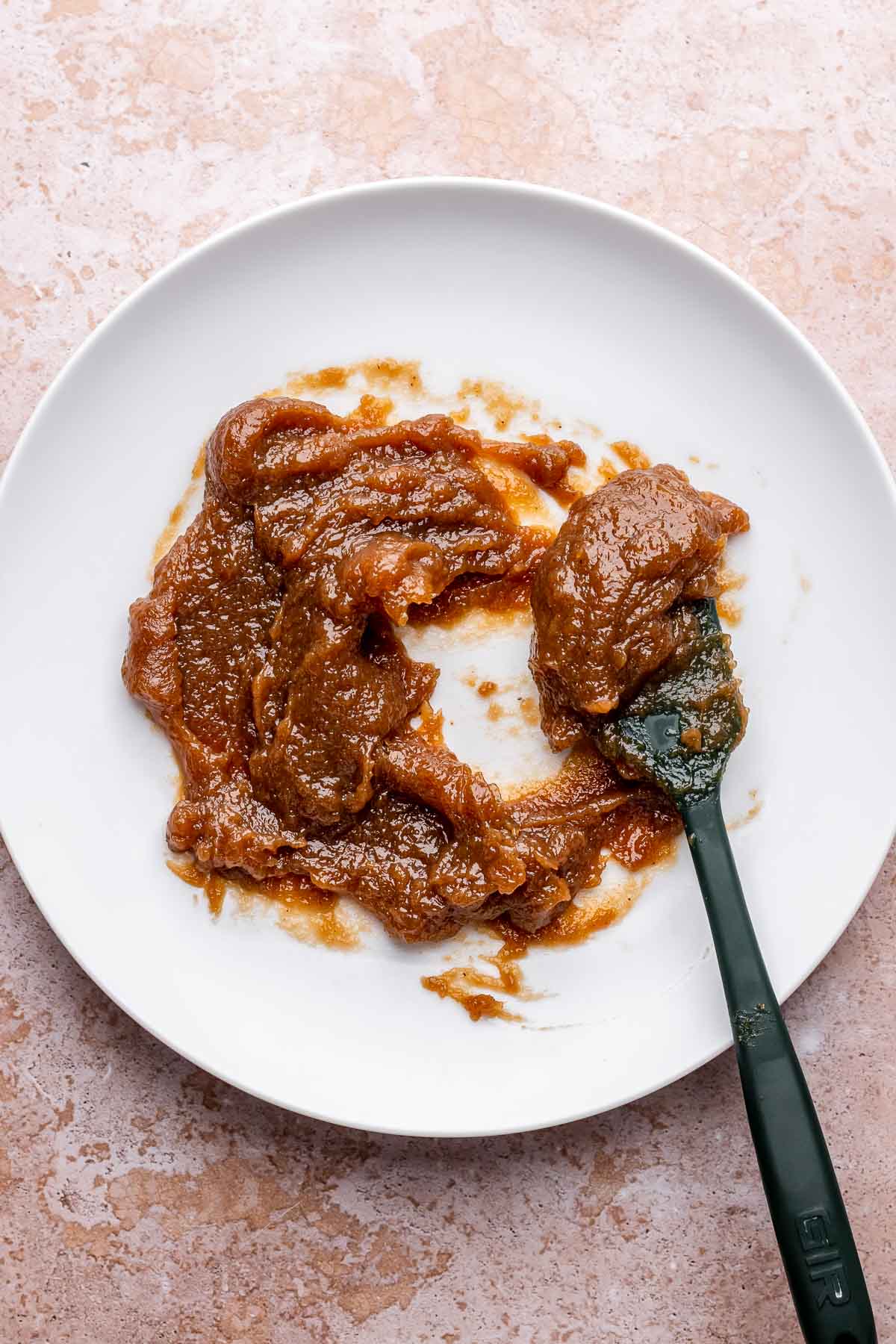 Thickened, cooled apple butter on a plate with a spatula.