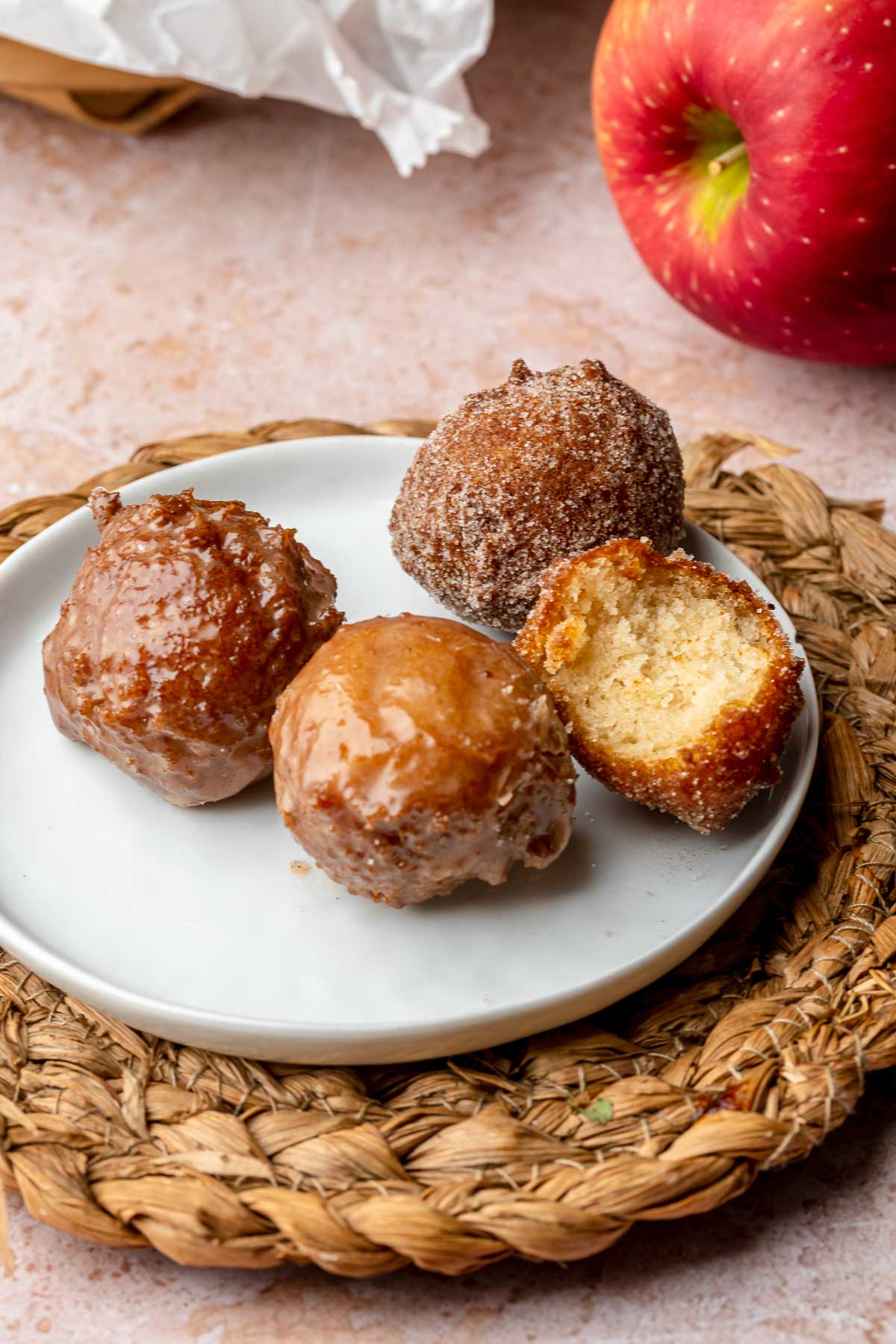 Apple cider donut holes on a plate. One has a bite removed.