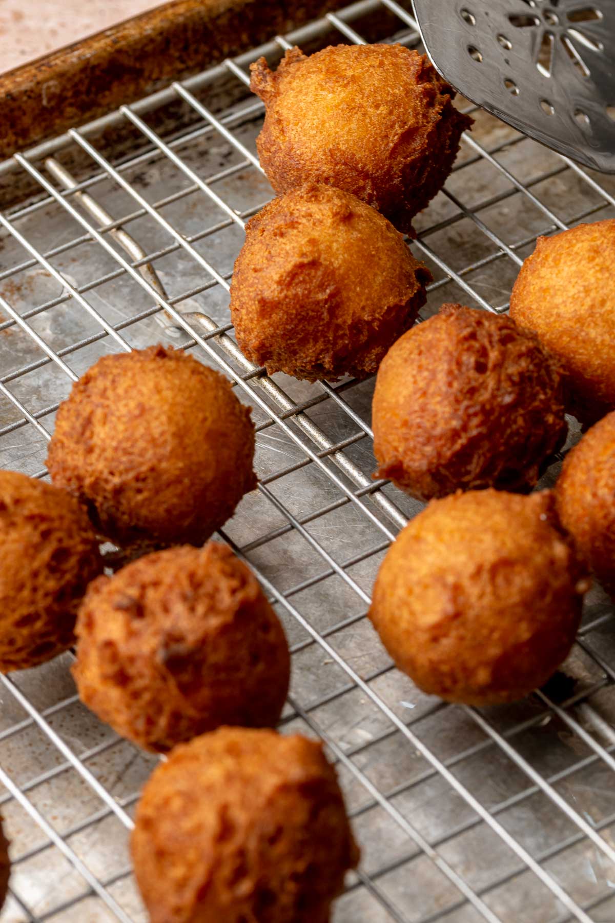 Fried apple cider donut holes on a wire rack.
