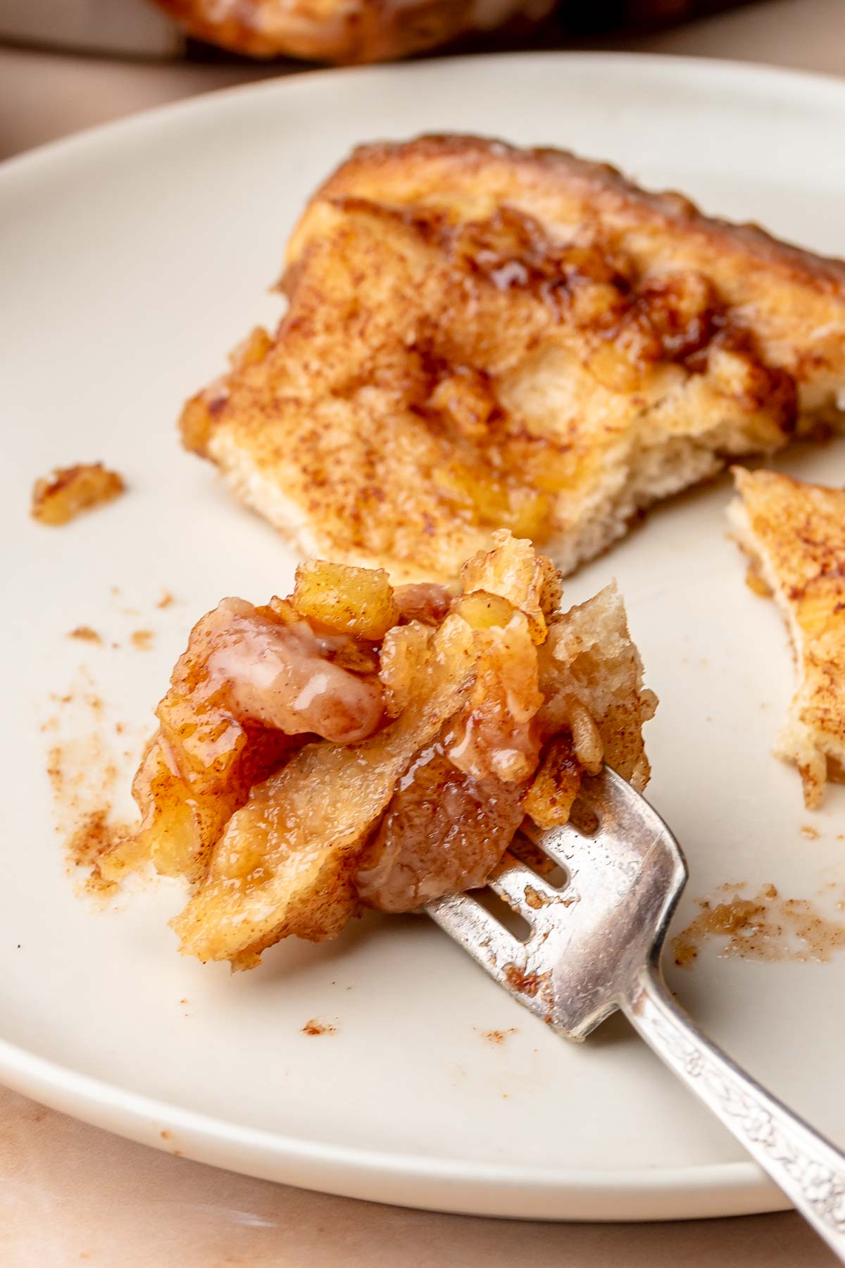 A piece of pull apart bread on a plate with a piece on a fork.