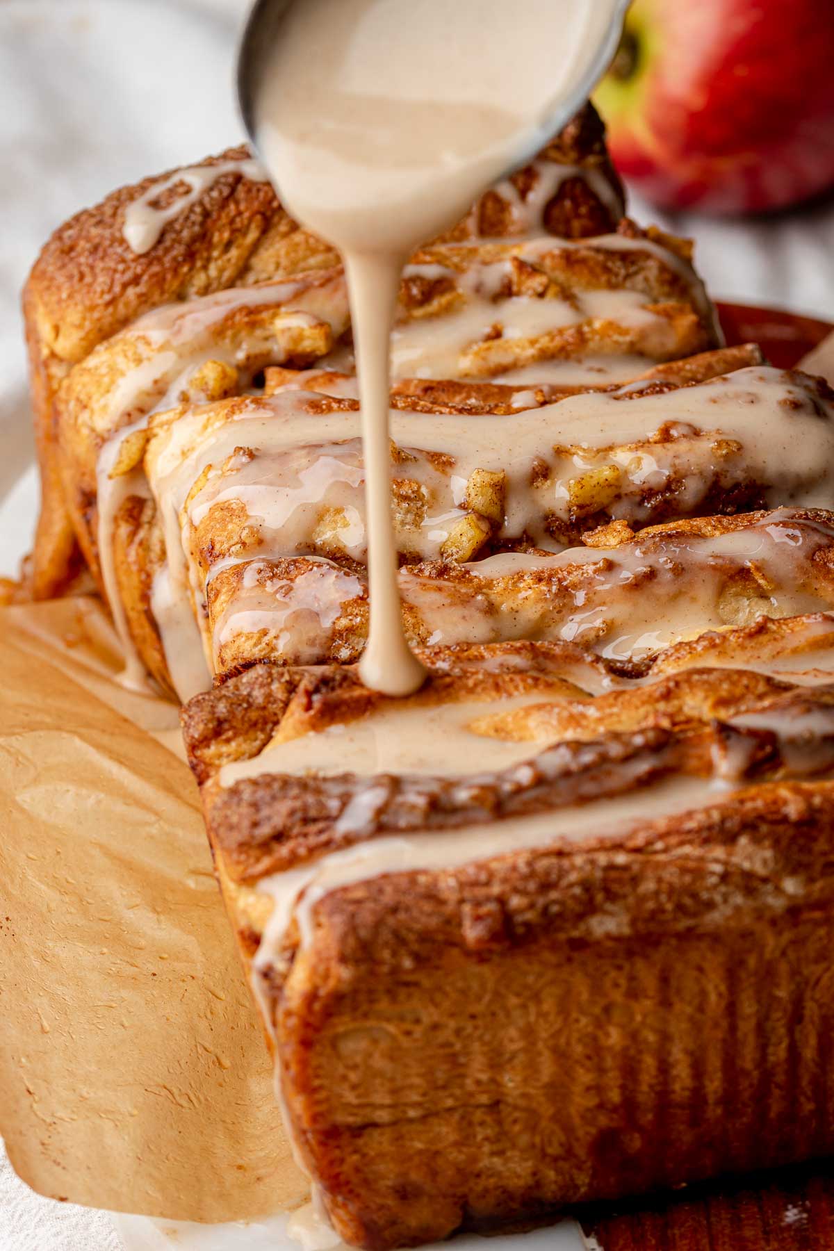 Cinnamon glaze being drizzled onto baked pull apart bread.