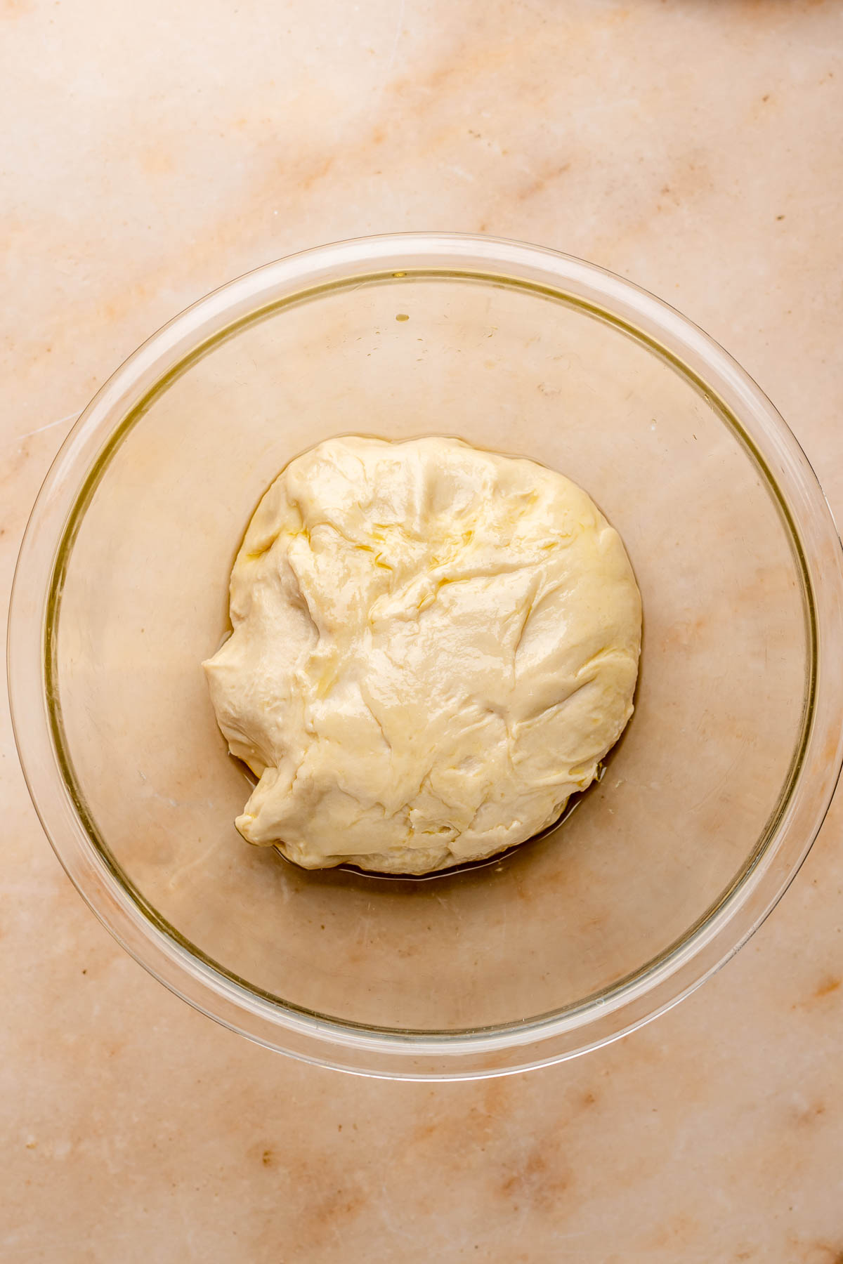 Greased dough in a bowl before rising.