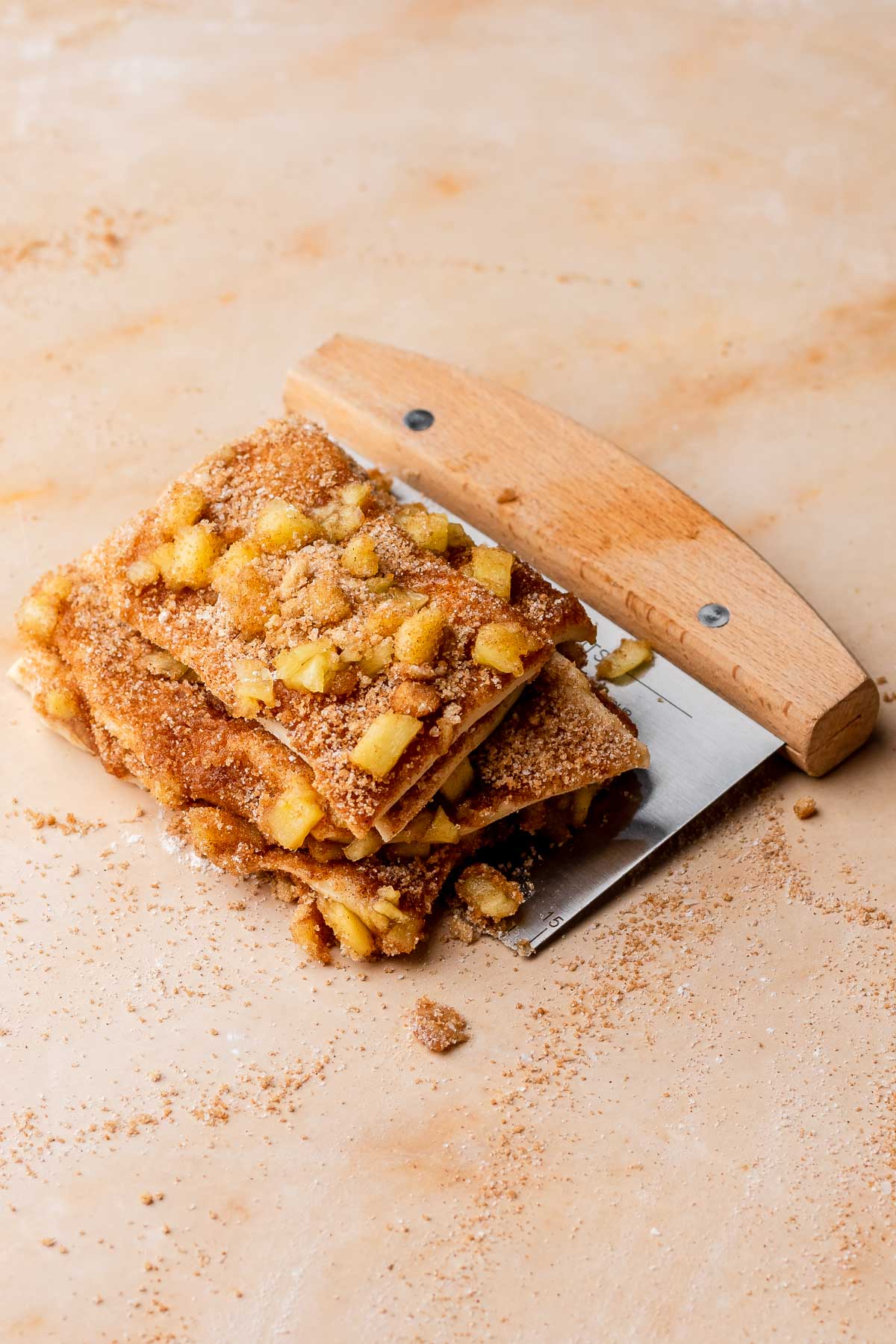 A stack of cut pull apart bread on a bench scraper.