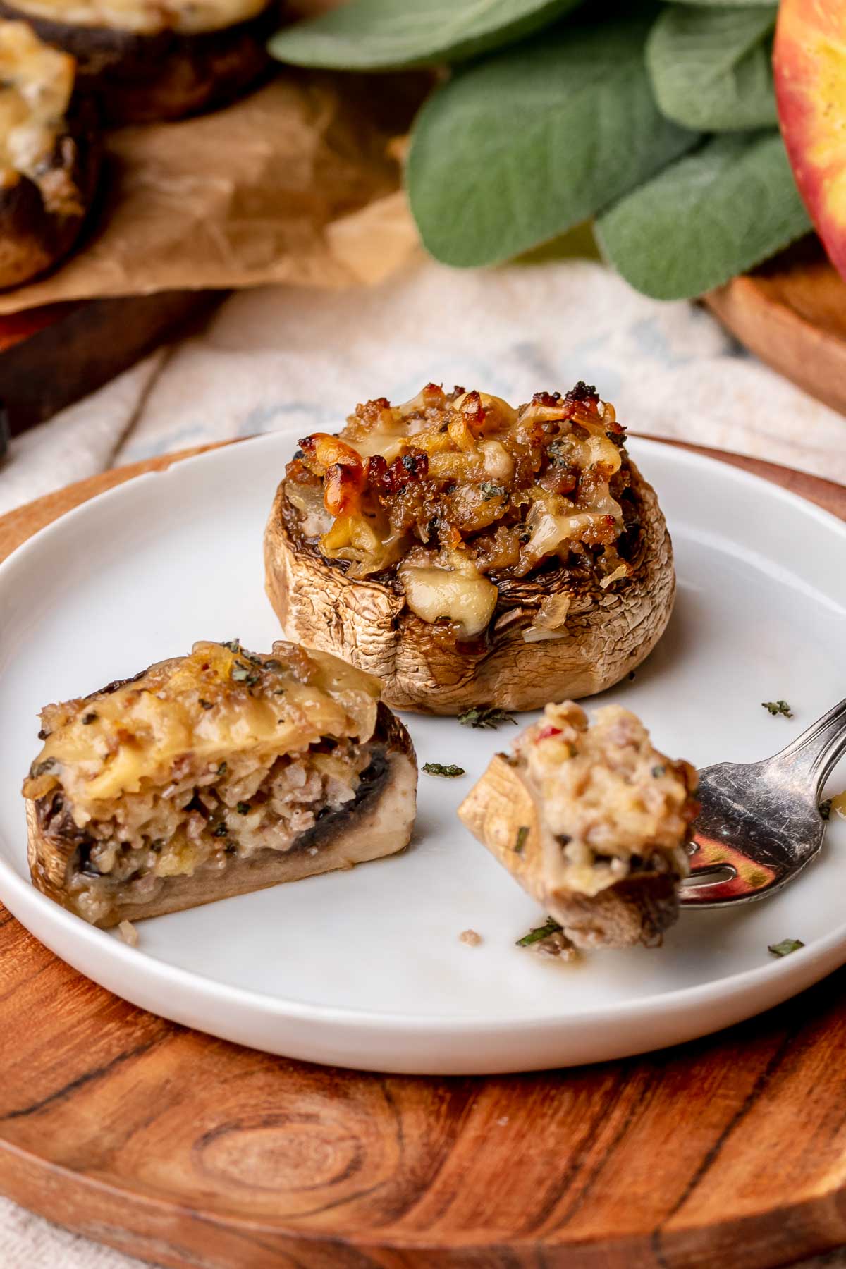 Sausage apple stuffed mushrooms cut apart on a plate.