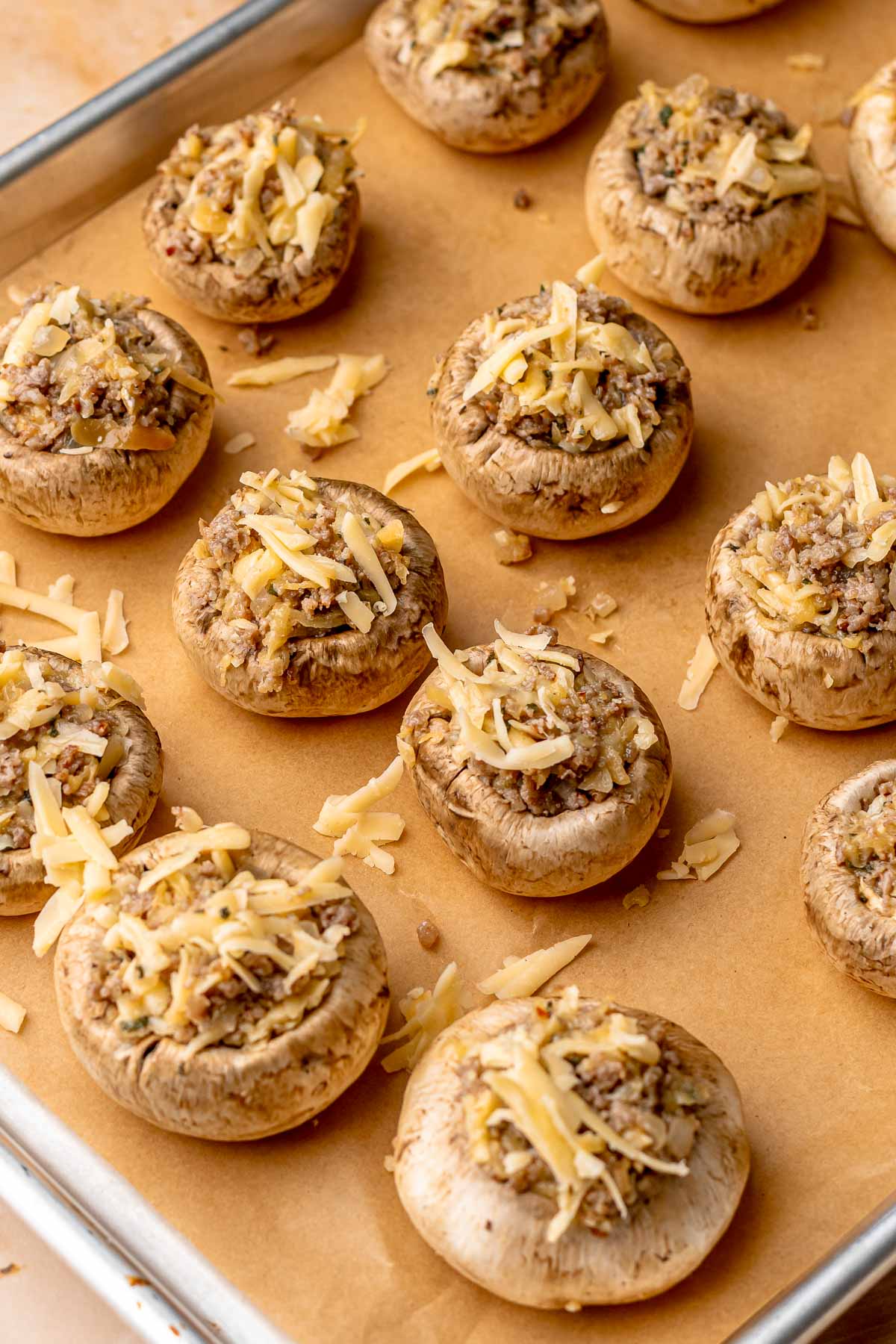 Filled, pre-baked sausage apple stuffed mushrooms on a baking sheet.