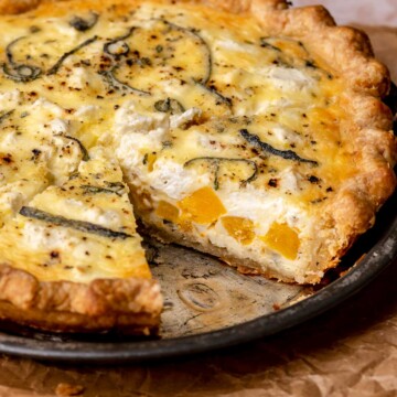 Baked butternut squash quiche in a pie dish with a slice removed.