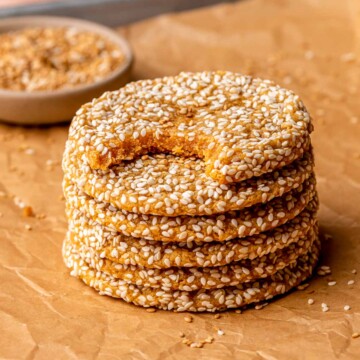 A stack of sweet potato sesame cookies on parchment paper. The top one has a bite removed.