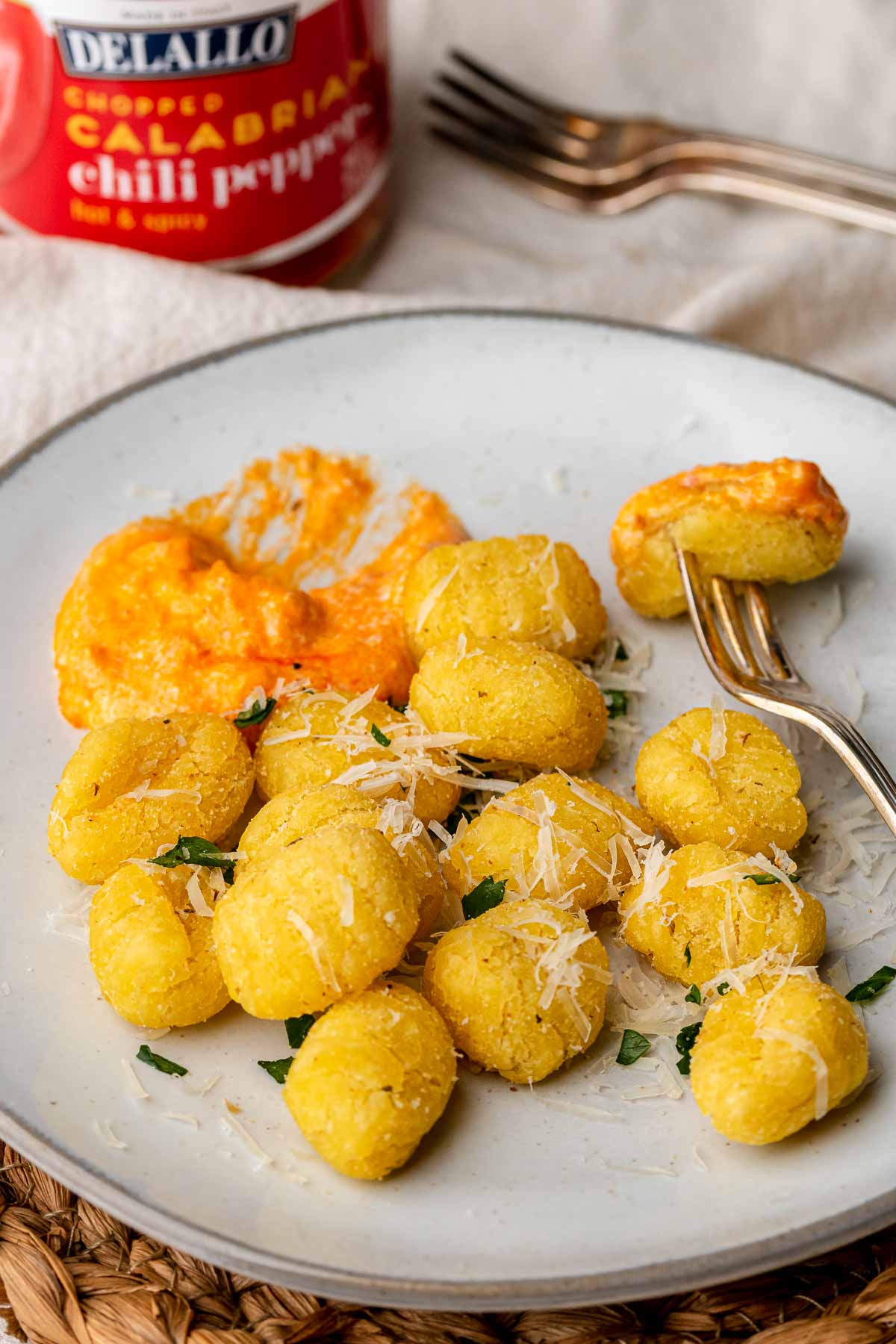Air fryer gnocchi on a plate with a cocktail fork and dip on the plate.