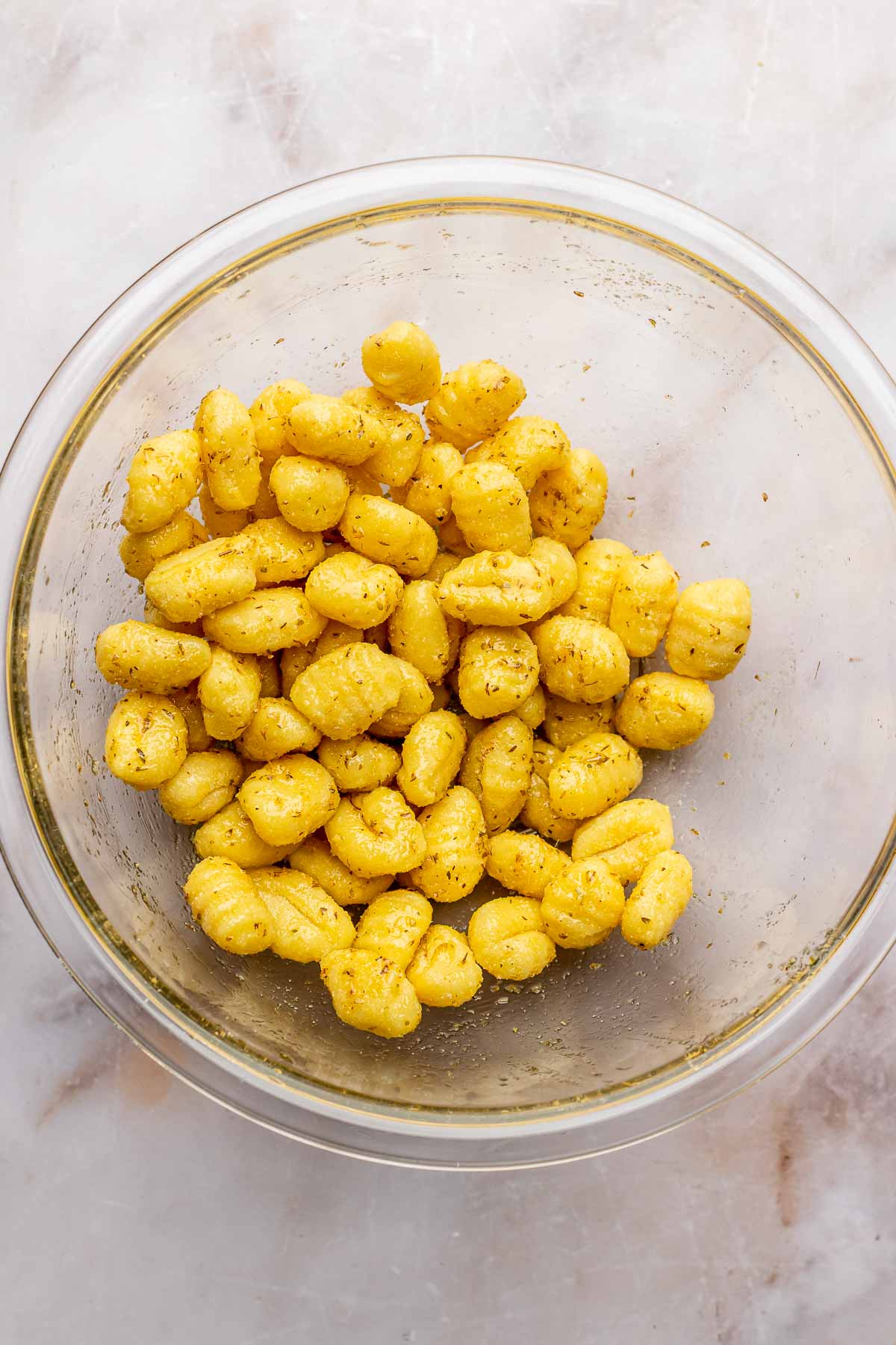 Pre-cooked gnocchi in a bowl tossed with spices.