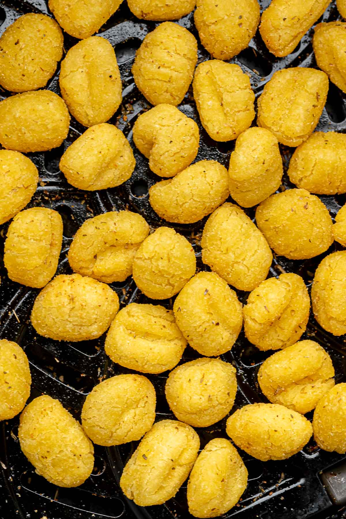 Crispy gnocchi in an air fryer basket.