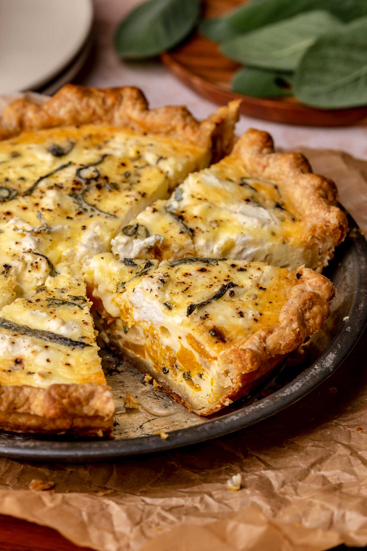 Baked butternut squash quiche in a pie dish with a slice removed.