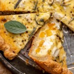 Baked butternut squash quiche in a pie dish with a slice on its side.