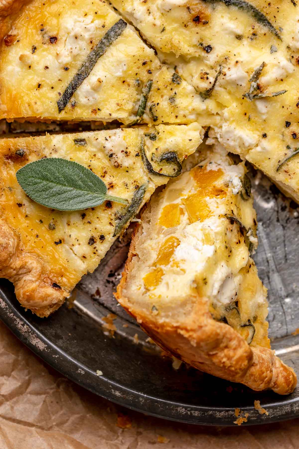 Baked butternut squash quiche in a pie dish with a slice on its side.