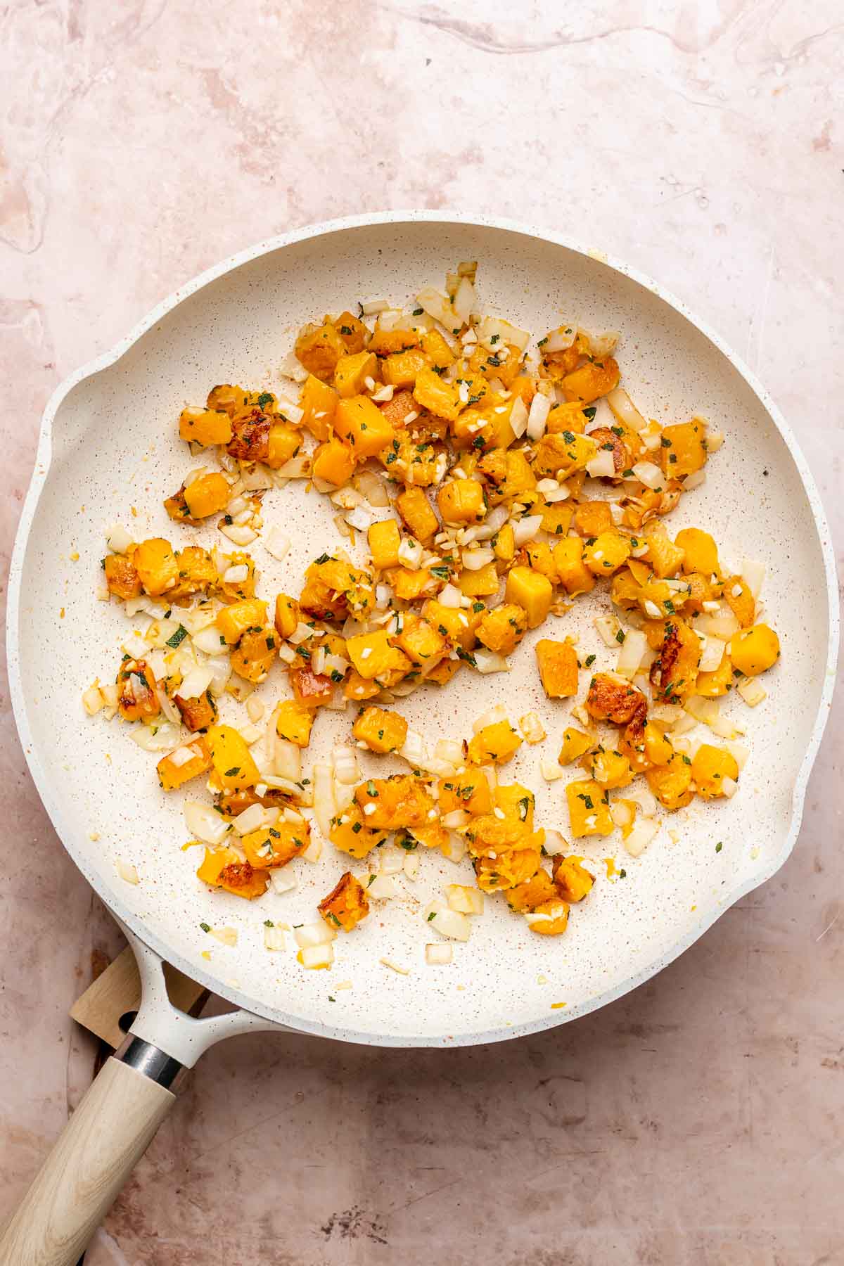 Pieces of butternut squash sauteed in a pan.