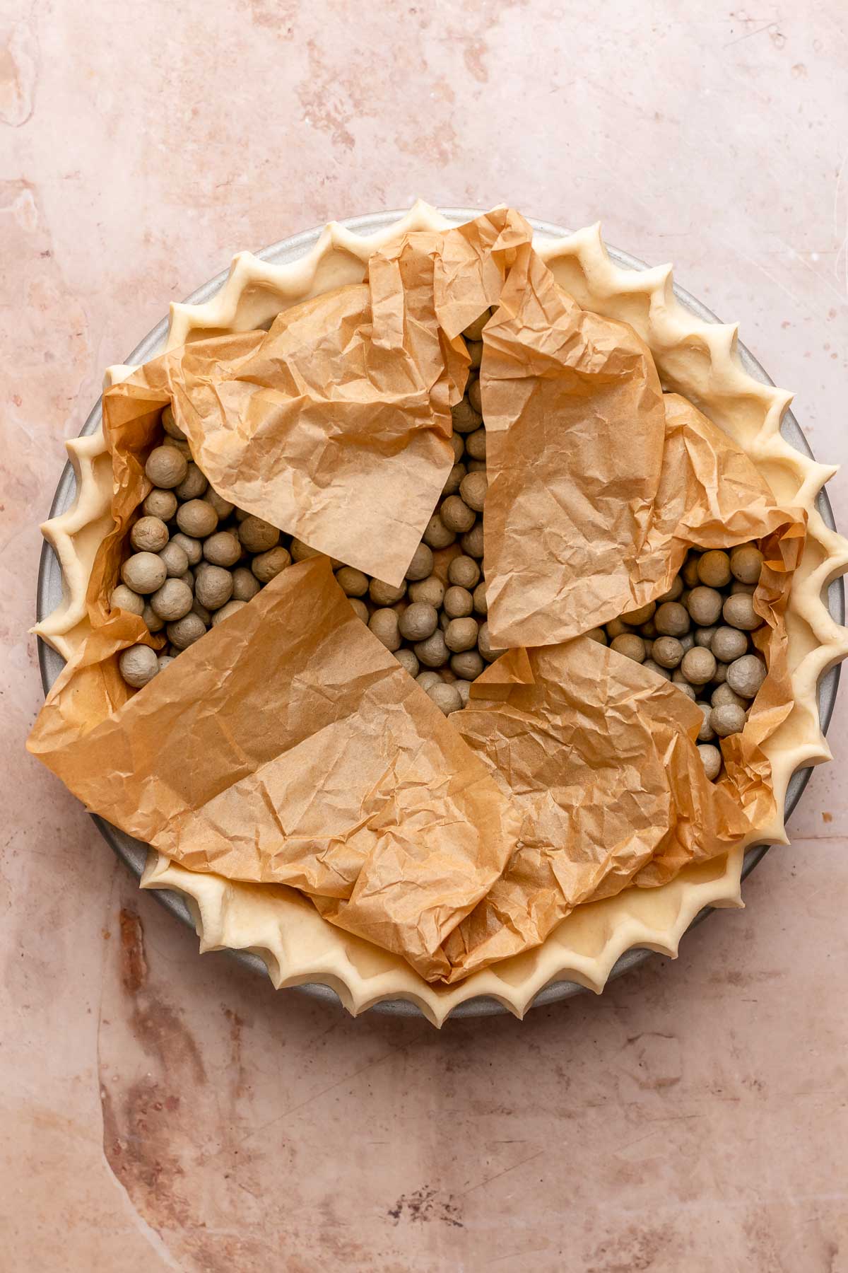 Pie crust with parchemnt paper and pie weights in the center.