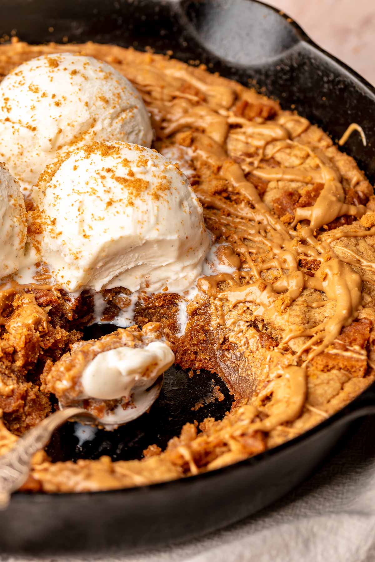 Baked cookie butter skillet cookie with ice cream on top and scoops removed from the center.