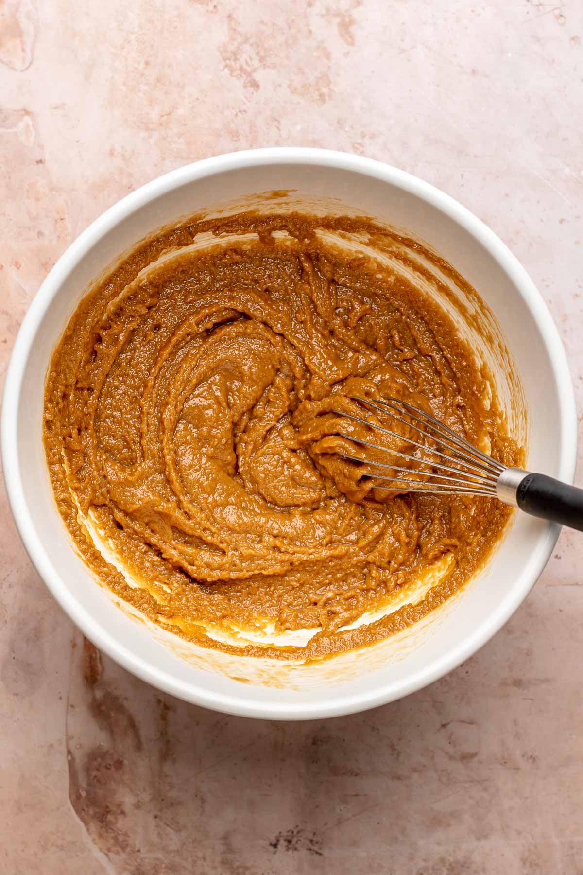 A whisk mixes cookie butter batter in a bowl.
