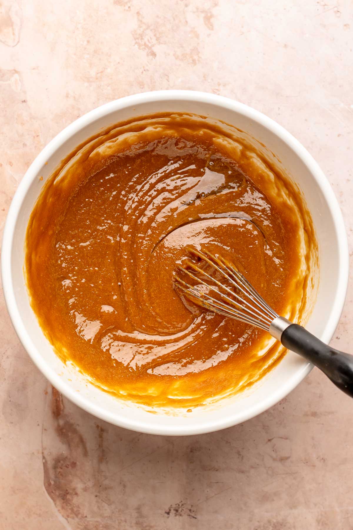 A whisk mixes cookie butter batter in a bowl.