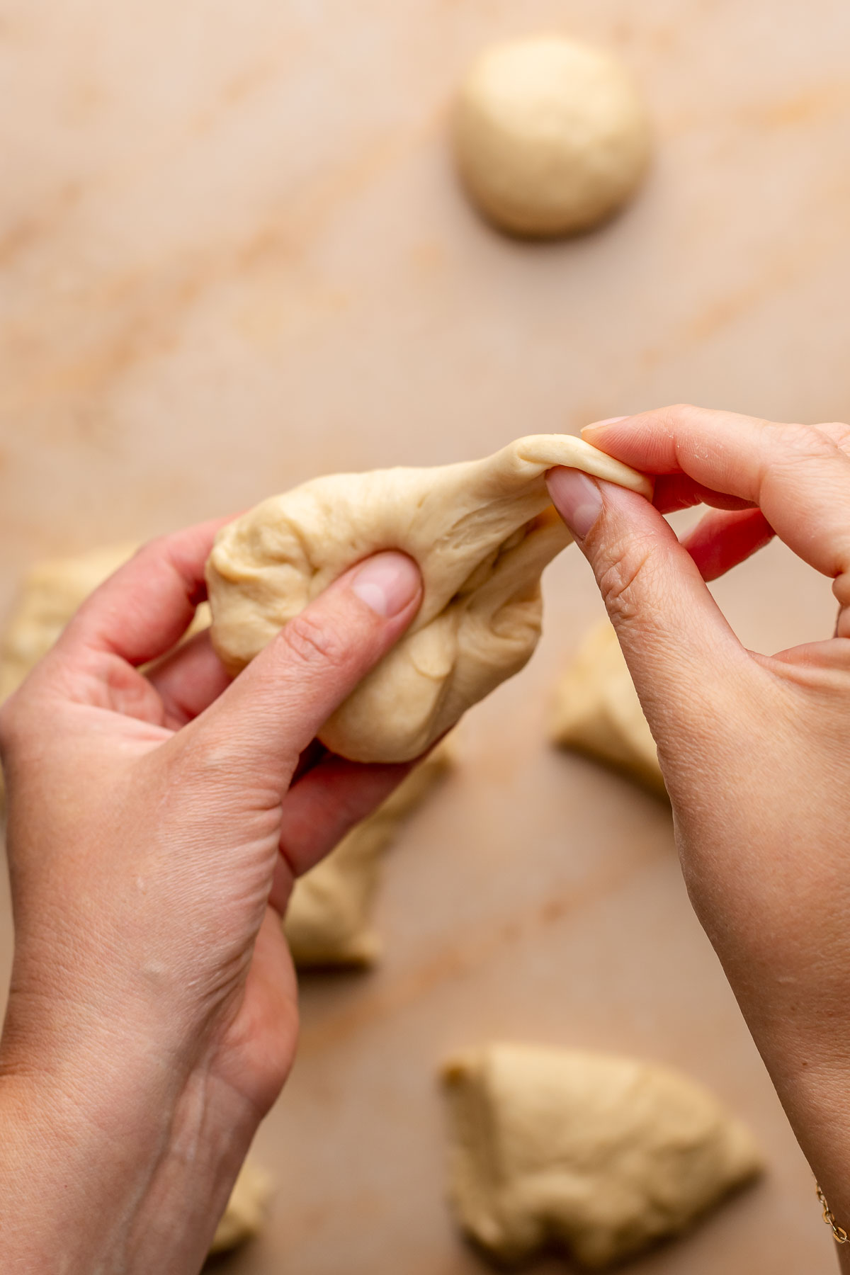 A hand stretches pieces of dough into a ball.
