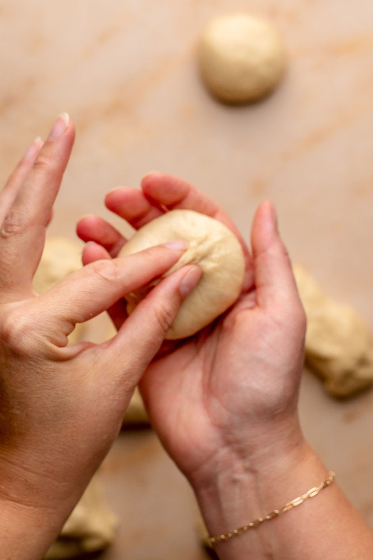 A hand pinches together a ball of dough to seal it.