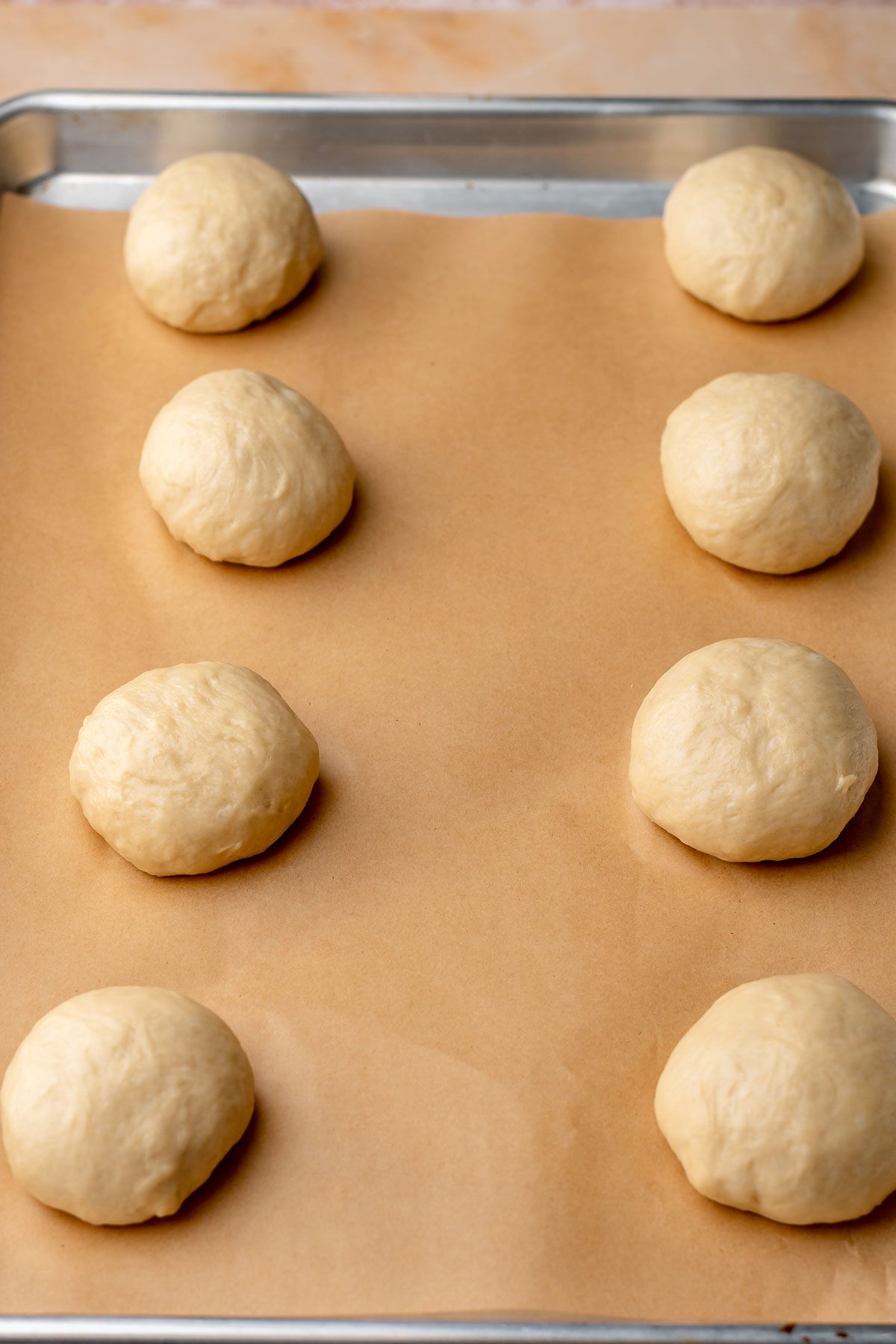 Balls of pre-risen brioche dough on a baking sheet.